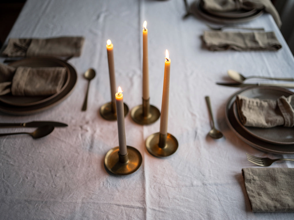 A dining table set with three staggered taper candles as the centerpiece