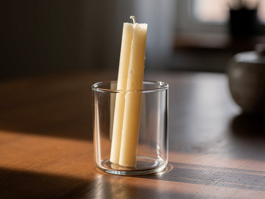 A taper candle sitting slightly crooked in a glass candle holder