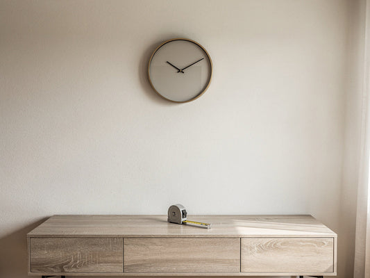 A wall clock hung at eye level above a console table in a living room.