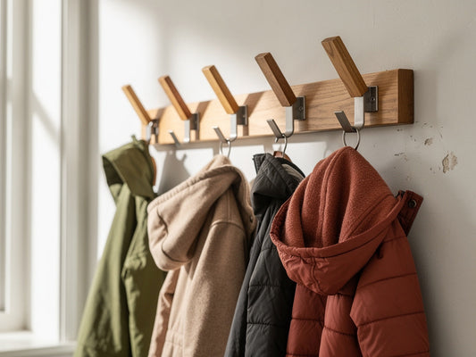 Coat hooks mounted at staggered heights on an entryway wall holding adult and child coats