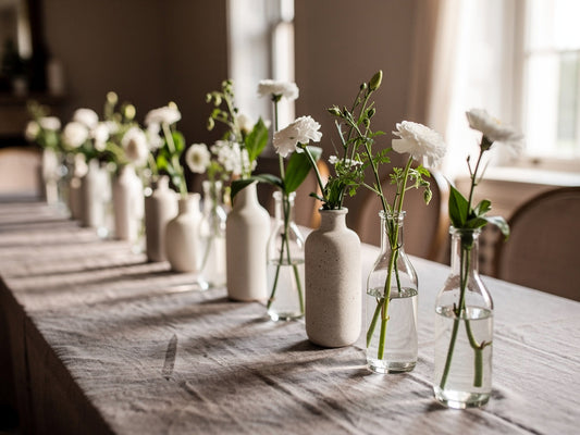 Wedding reception table with a row of reusable bud vase centerpieces